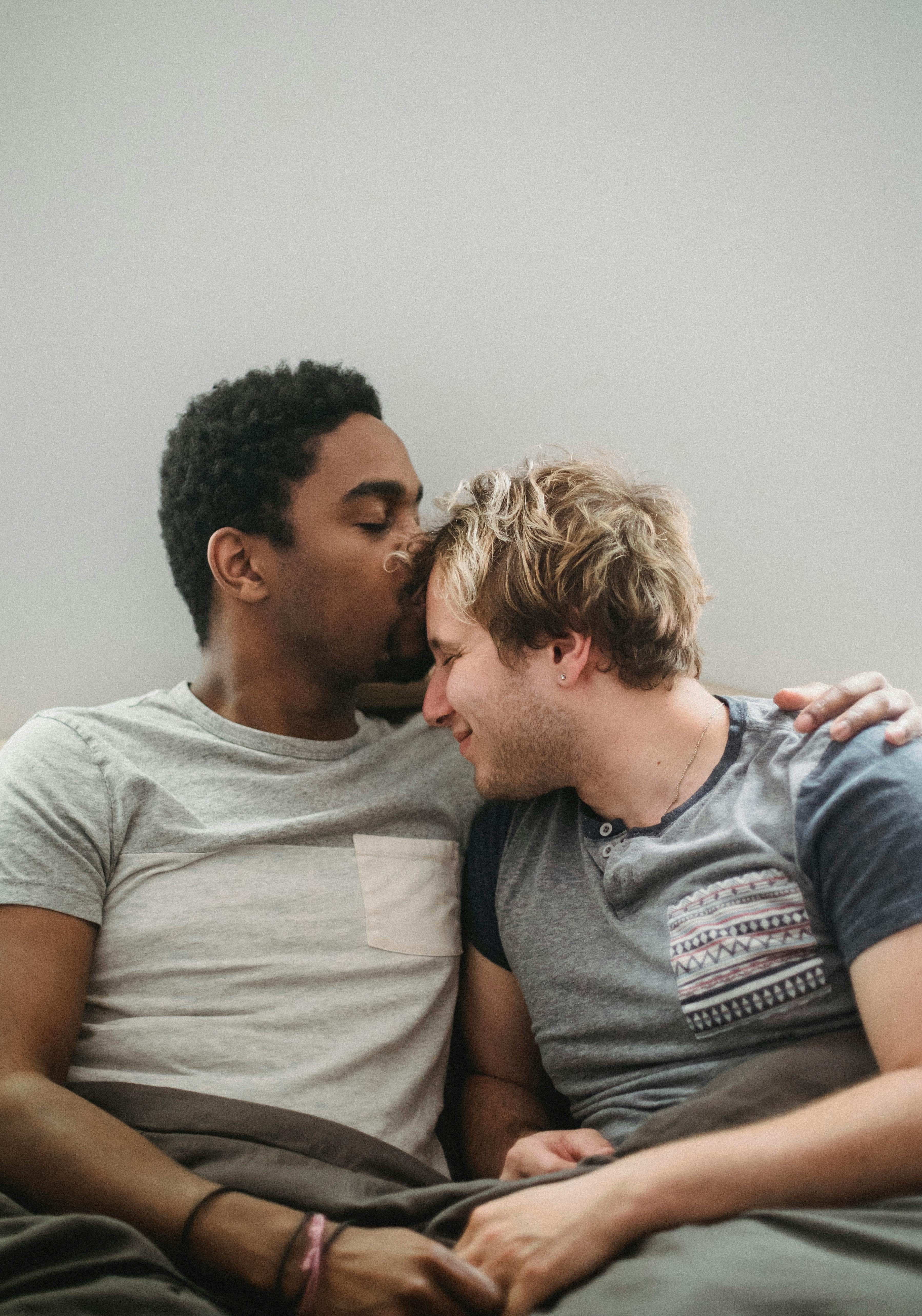 man kissing another man on the forehead