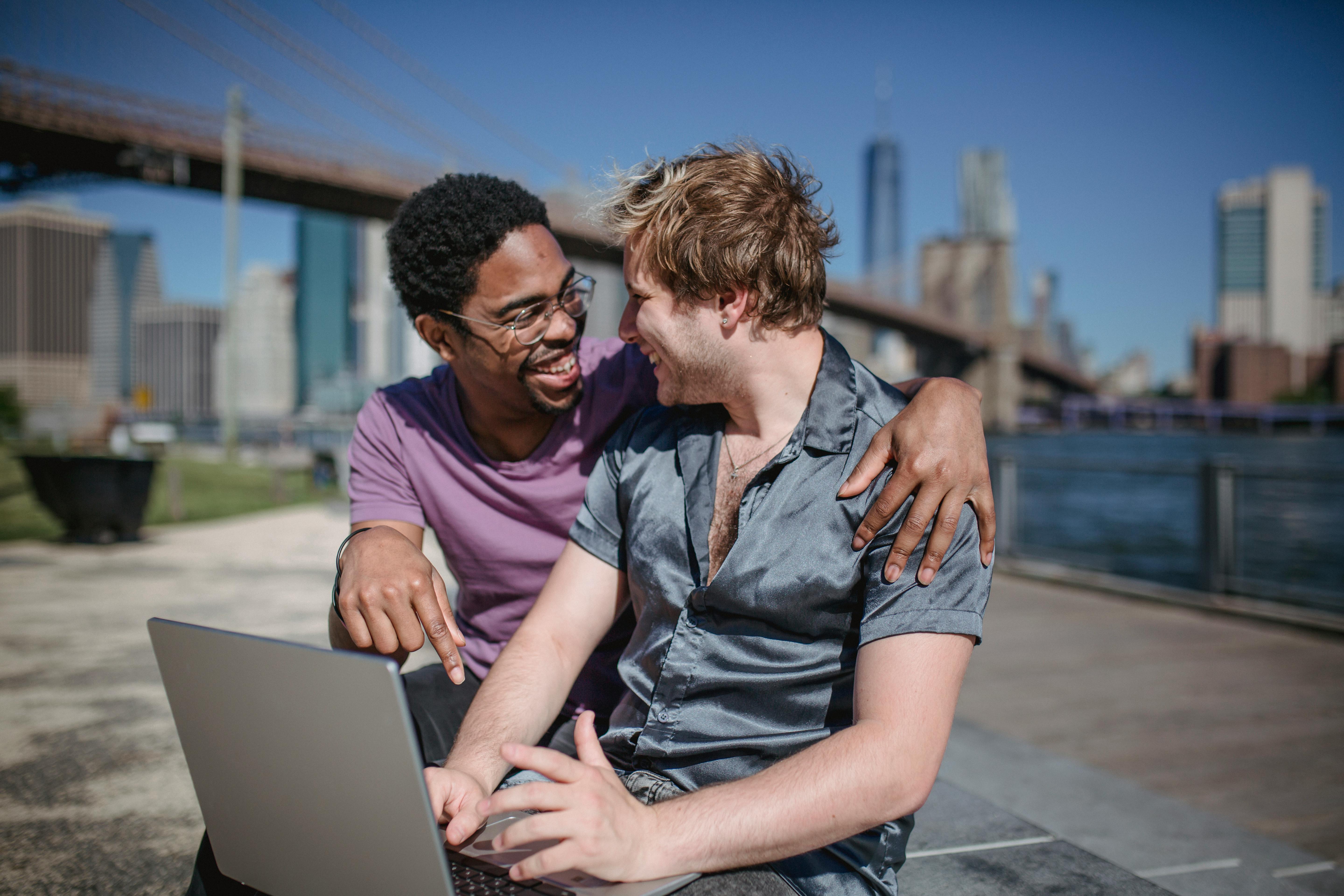 two men smiling and using a laptop