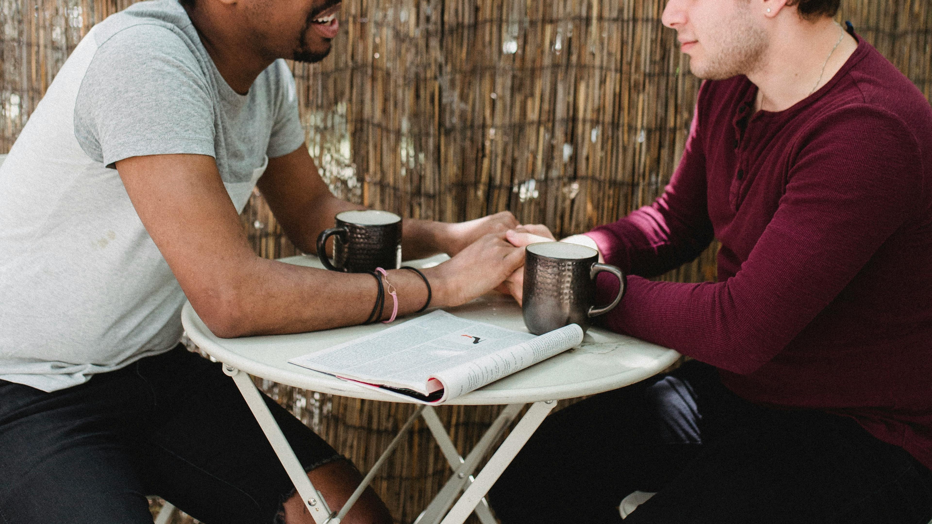 two men sitting and holding hands