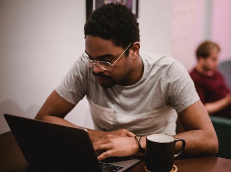 Two young men working on laptops in a cozy cafe environment, focusing on projects.