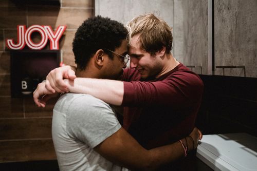 Free An interracial LGBTQ couple shares a joyful and intimate embrace indoors. Stock Photo
