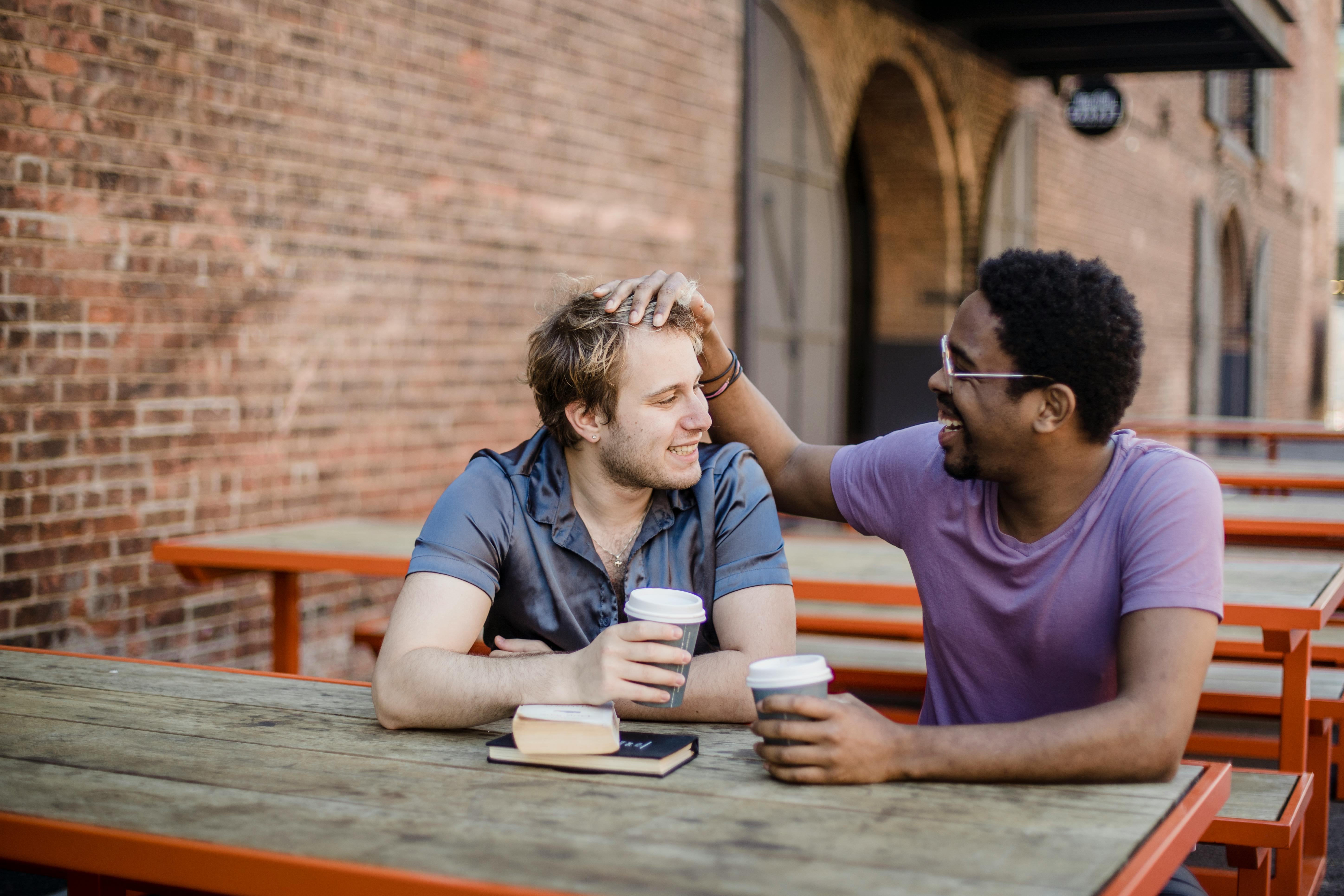 two men sitting outside and being affectionate