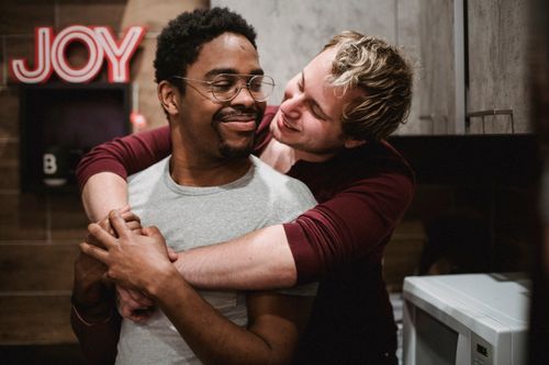 Free Loving gay couple sharing an affectionate embrace in a cozy indoor setting, evoking joy and togetherness. Stock Photo