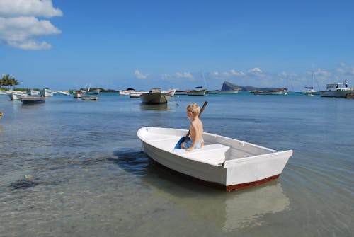 Free A Boy in a White Boat Holding a Paddle Stock Photo