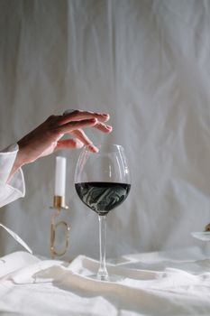 一只手伸向烛台附近的酒杯，场景是古典风格