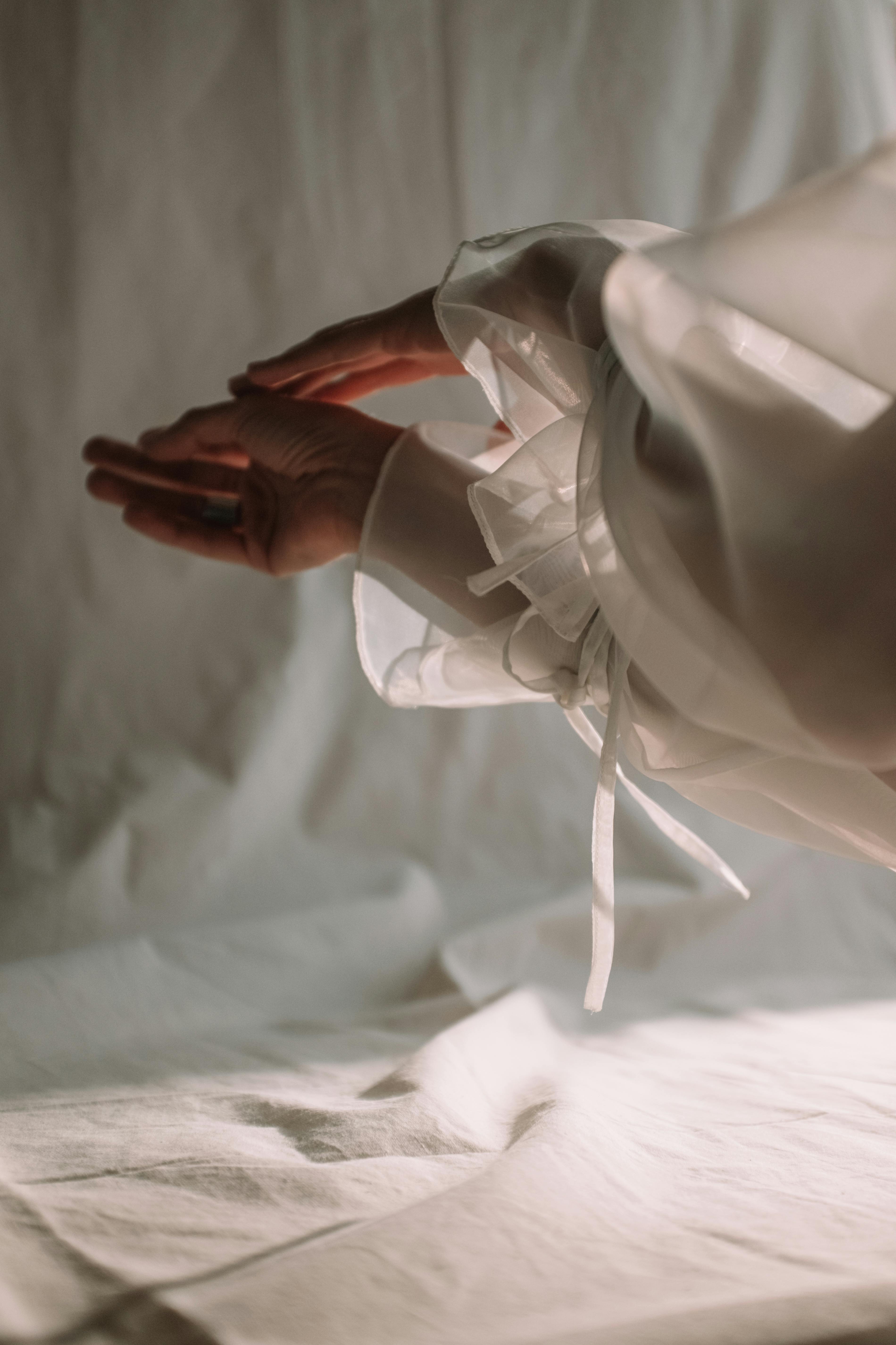 Elegant hands draped in flowing white fabric, showcasing grace and sophistication.