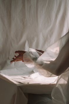在柔和的灯光背景下，半透明的丝绸面料覆盖着优雅的手臂，散发着优雅的气息