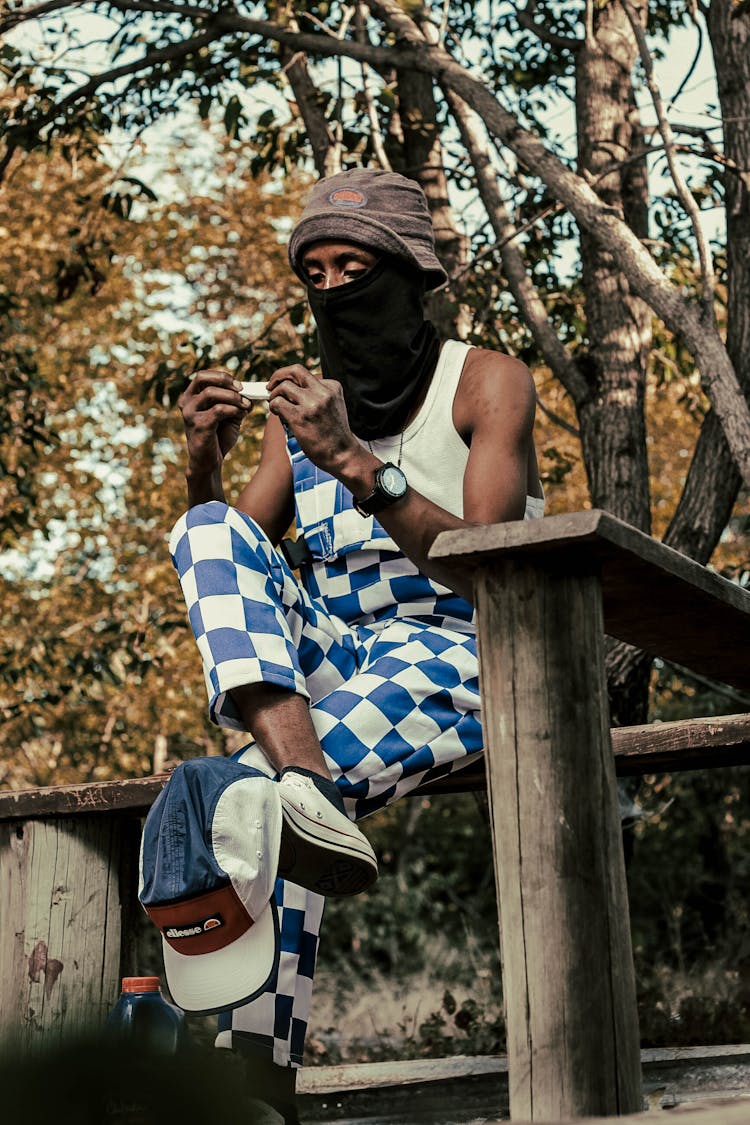 Black Man Sitting On Wooden Bench With Knife