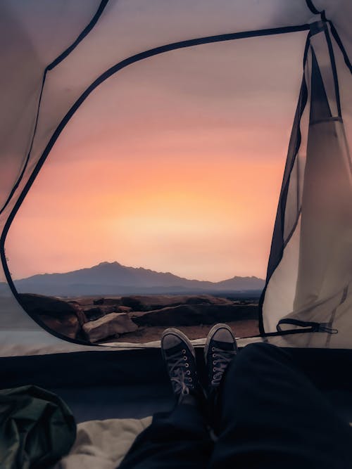 Free Traveler lying in tent and enjoying bright sunset light Stock Photo