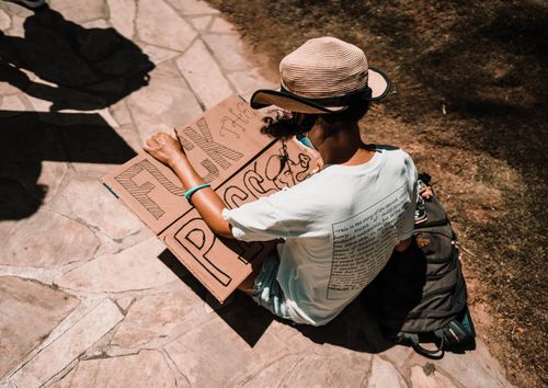 Free Person sitting on pavement holding a protest sign in Honolulu, Hawaii. Stock Photo