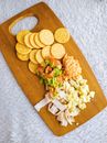 Crackers, Guacamole, Ham and Hummus on a Cutting Board 