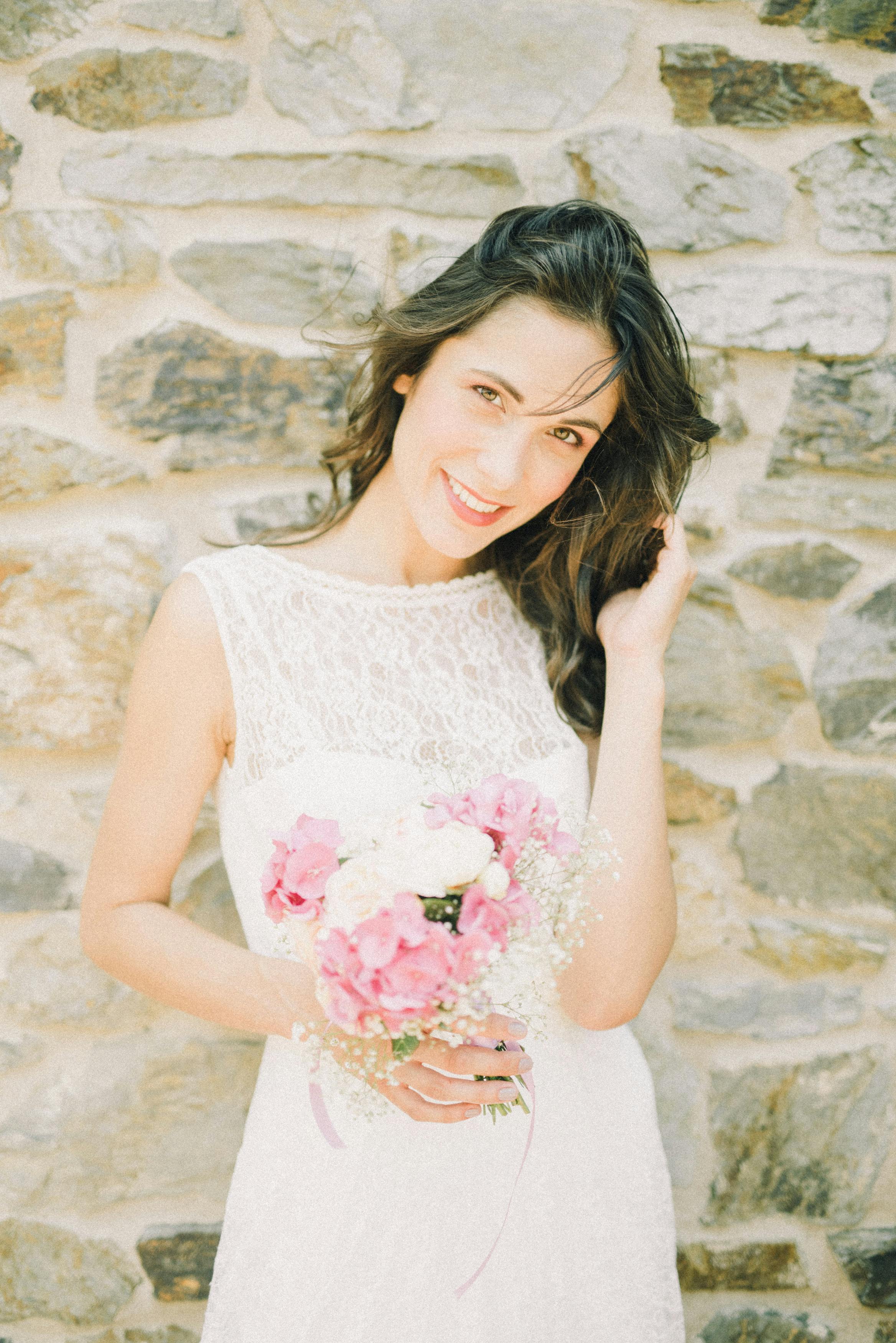 woman in white floral sleeveless dress holding pink rose bouquet