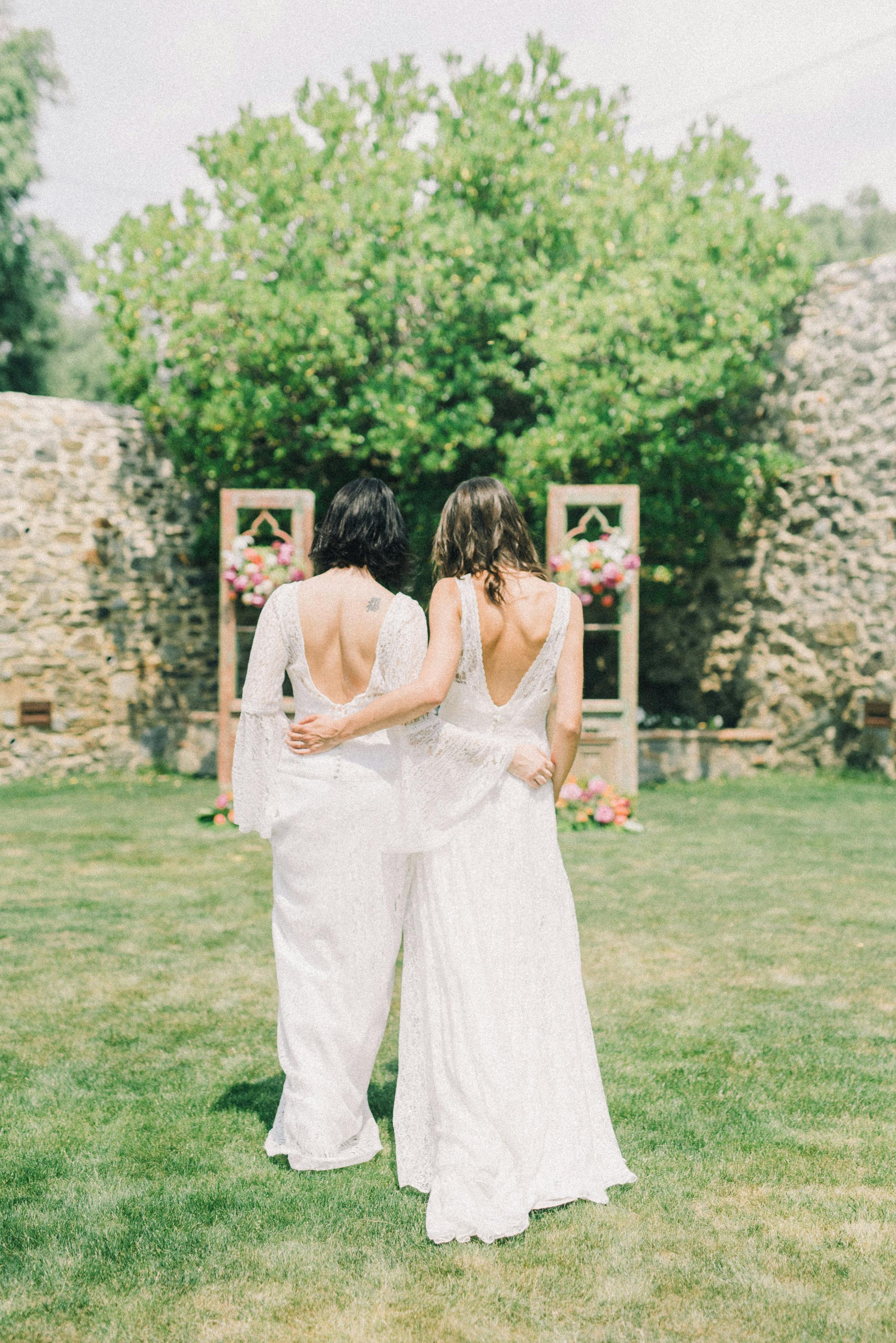 photo of women in white wedding dress walking on grass