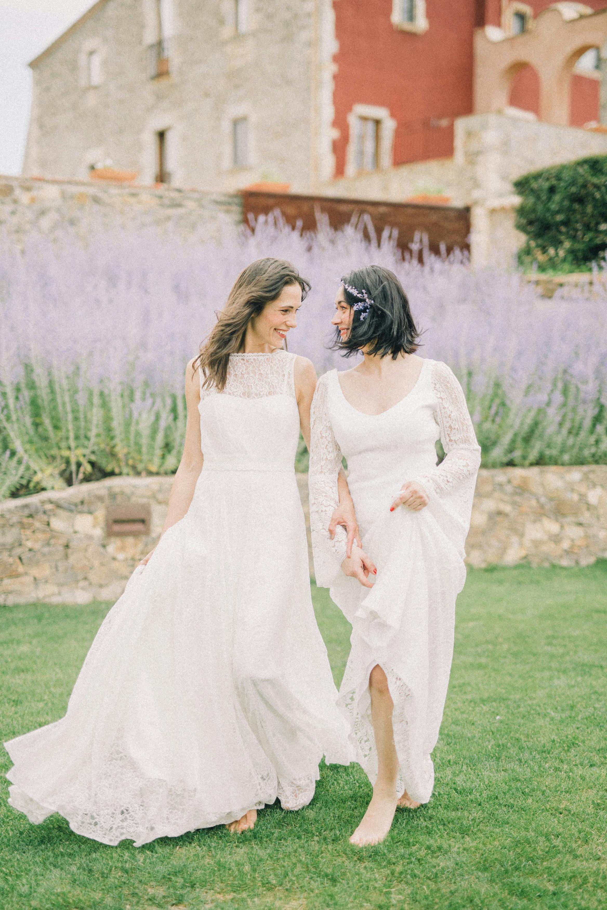 photo of two women looking at each other while walking on grass field