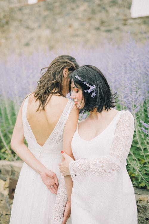 Photo of Women in White Wedding Dress Standing Next to Each Other