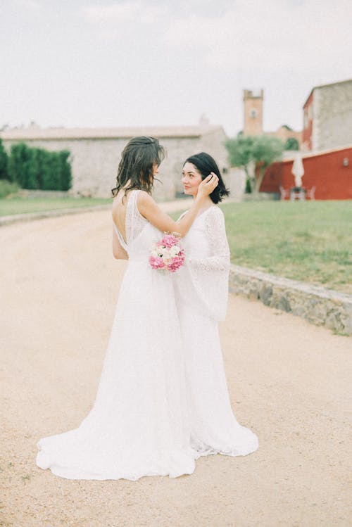 Photo of Women in White Wedding Dress Looking at Each Other