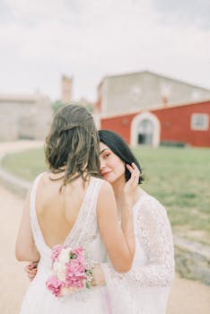 A loving outdoor moment between a lesbian couple on their wedding day, embracing with happiness.