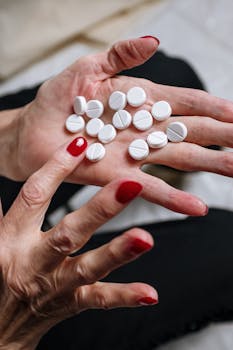 A woman's hand with red nail polish holding white pills, indicating a medical or health theme.