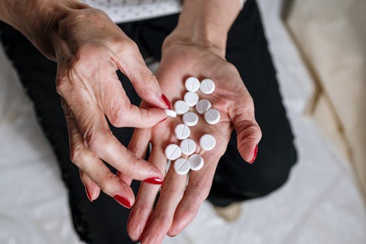 Senior woman's hands with red nails holding circular white tablets, depicting medication concept.