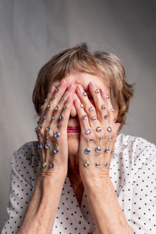 Woman in White Shirt Covering Her Face With Her Hands