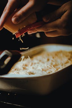 A chef grates cheese over a dish, capturing a rustic kitchen ambiance.