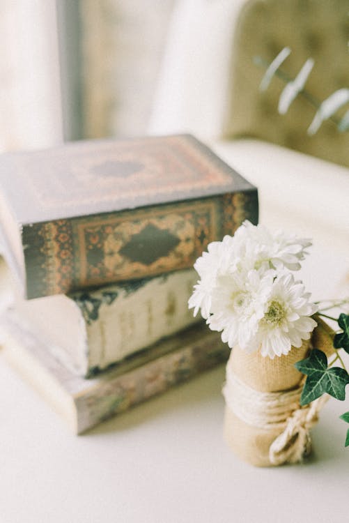 White Flowers Near Stack of Books