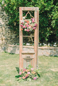 Rustic wooden wedding arch adorned with colorful flowers outdoors in a garden setting.