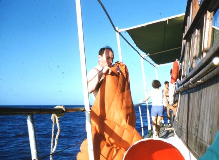 A Man Inflating An Inflatable Orange Boat