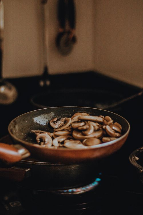 Free Delicious sliced mushrooms being sautéed in a frying pan on a stove. Stock Photo