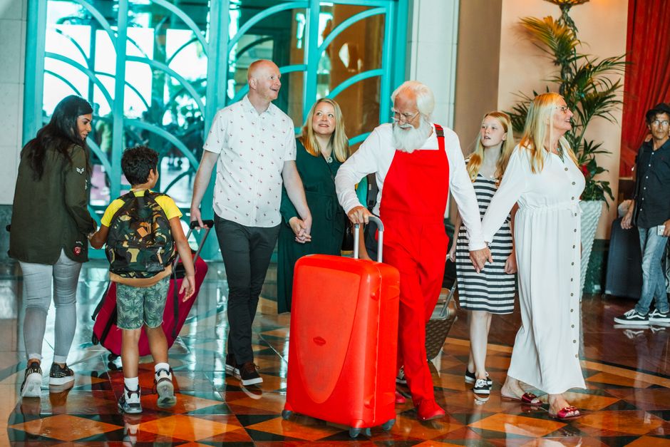 Família diversa chega feliz a um hotel de luxo em Dubai com malas coloridas. Férias em família.