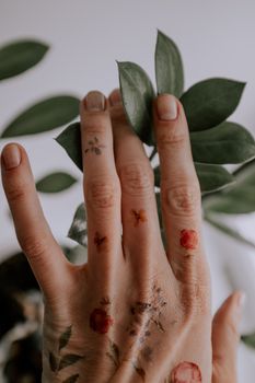 特写镜头中，纹身的手轻触绿叶，展现了自然与艺术的交融