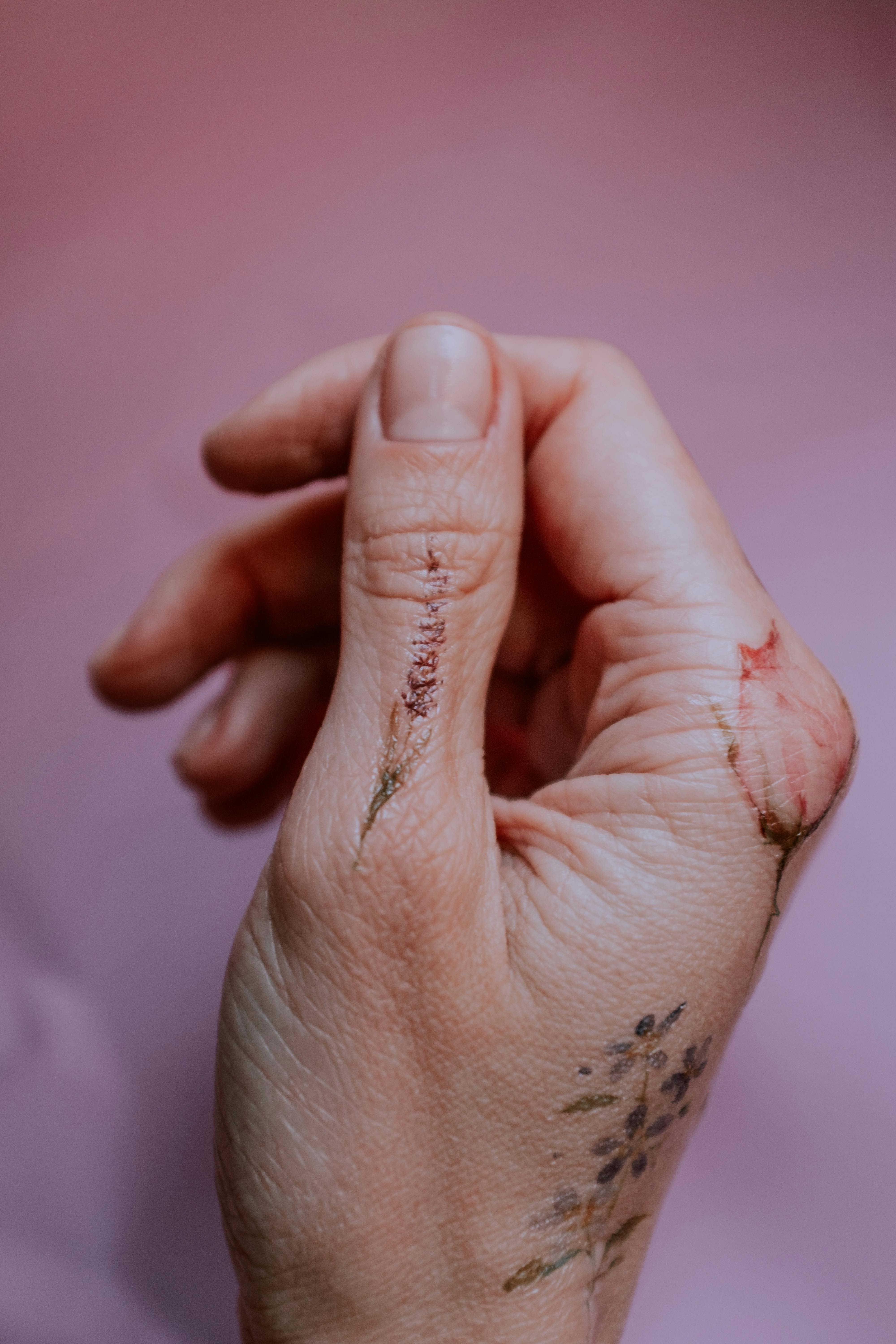 Generate an image of a top view of a light-skinned human hand. between the  thumb and index finger, distinctly ink a dark, bold semi-colon (;) tattoo.  this semi-colon symbolizes mental health awareness