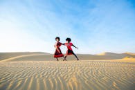 在阿联酋迪拜的沙质沙漠中，两名舞者优雅地穿行于晴朗的蓝天下