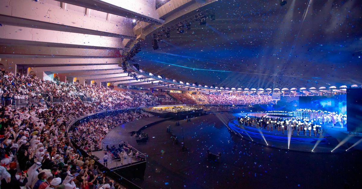 A panoramic view of the interior of Christ Embassy Loveworld Arena, showing the massive stage, audience, and dynamic lighting