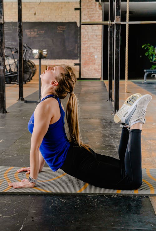 Woman in Blue Tank Top and Black Leggings Doing Yoga