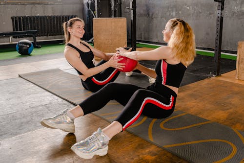 Free Photo of Women Sitting on Floor While Holding an Exercise Ball Stock Photo