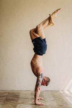 Fit adult man doing a handstand exercise indoors, showcasing balance and strength.