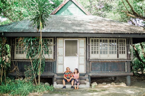 Photo of Couple Sitting in Front of House
