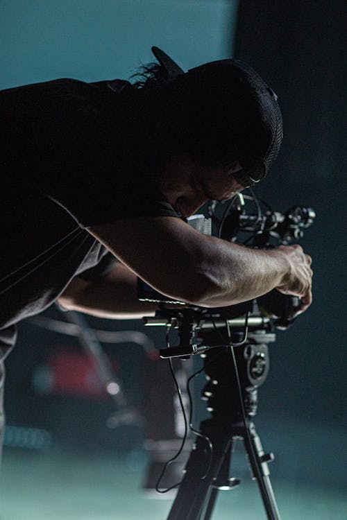 Unrecognizable black cameraman filming video on camera at work