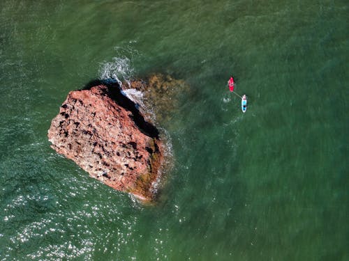 Aerial Shot of Brown Rock Formation in the Middle of Water