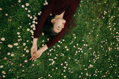 Free Top view of a woman relaxing in a lush flowered field, eyes closed. Stock Photo