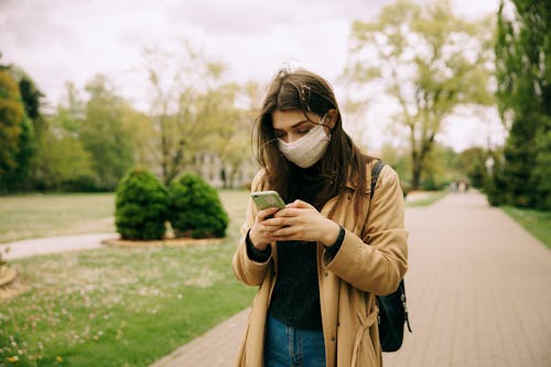 Free Woman in Brown Coat Texting While Walking Stock Photo