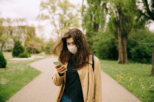 Free Woman in Brown Coat Holding Green Smartphone Stock Photo