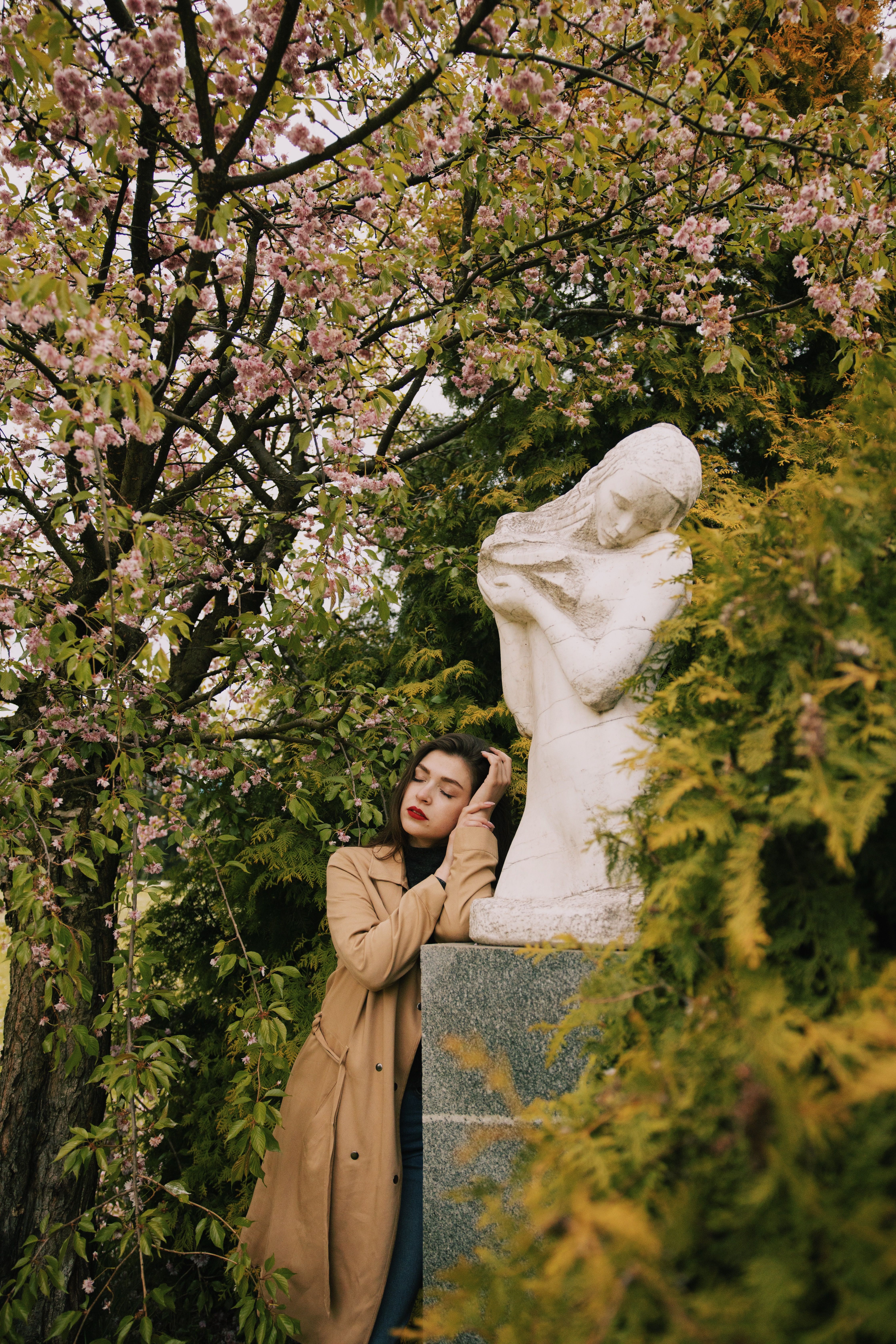Photo of Woman in Brown Coat Leaning on Statue · Free Stock Photo