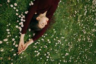 草地上盛开着雏菊，女人安静地躺着，体现了放松与自然的联系