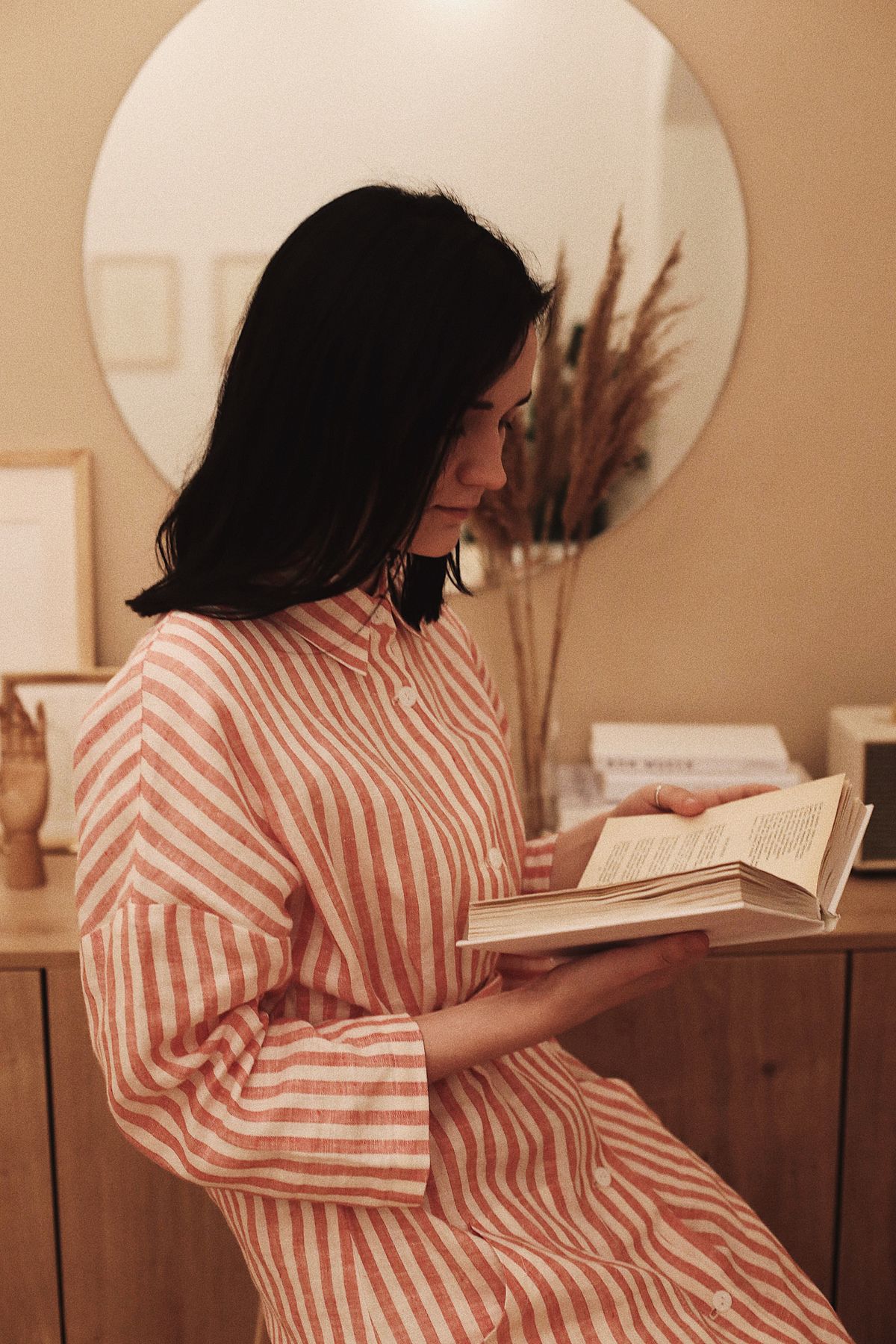 A woman in a striped long-sleeve shirt reading a book