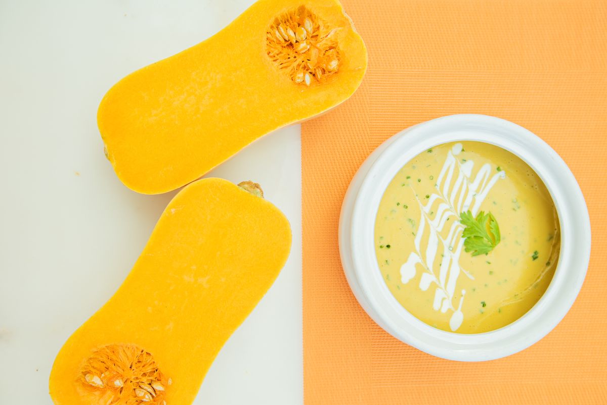 Creamy butternut squash soup next to halved butternut squash, a fall dish to pair with oaked Chilean Chardonnay