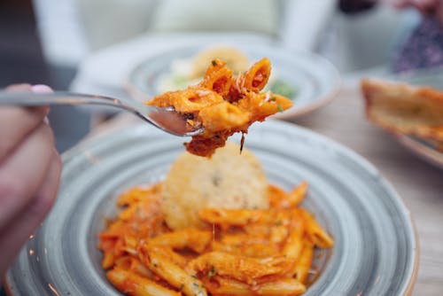A Person Holding Silver Fork with Cooked Pasta