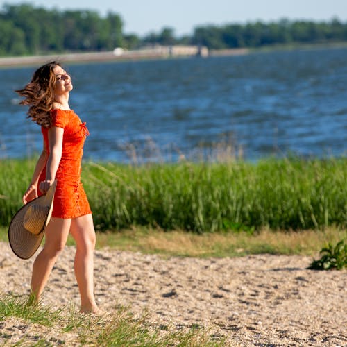 Woman in Orange Dress Walking on Sand