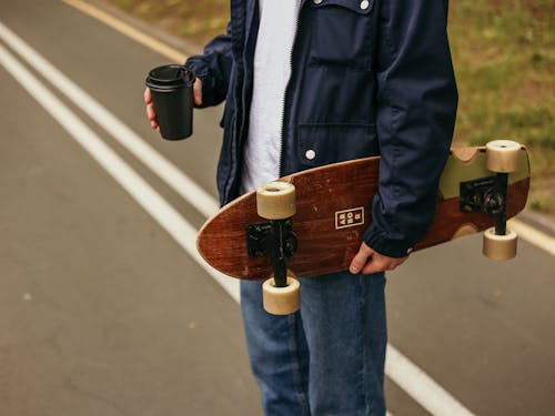 Person in Blue Denim Jacket Holding A Skateboard